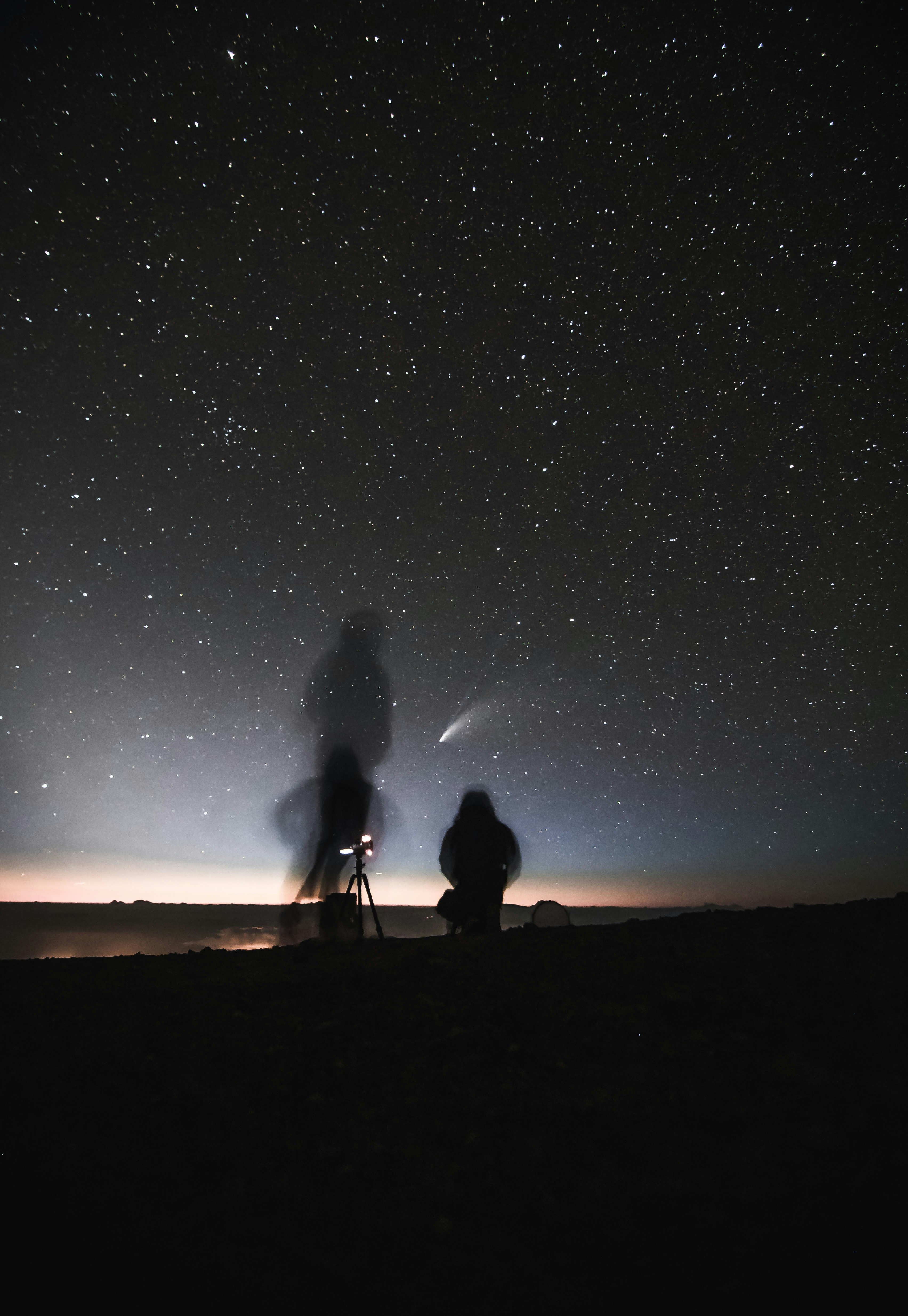 silhouette of 2 person standing on hill during night time